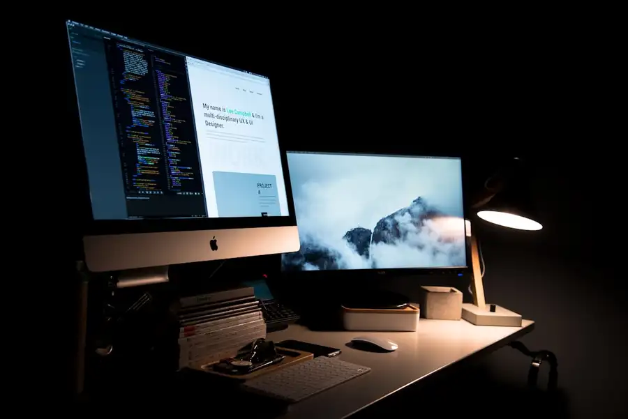 Mesa de estudo à noite, com dois monitores acesos